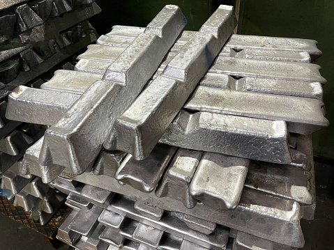 aluminum alloy ingots stacked in the foreground, ready for casting, raw material
