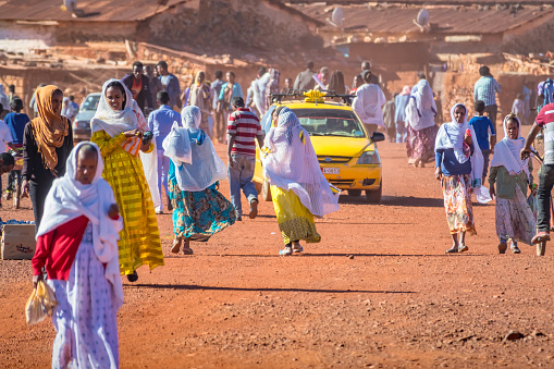People walk on a dirt road in Asmara, the capital of Eritrea, East Africa, on a sunny day.