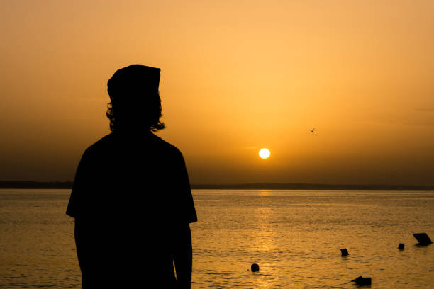 istock Young man watching the sunrise at the beach 1297870921