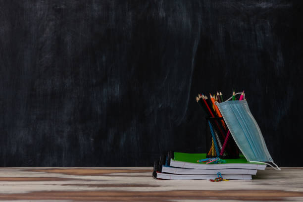 istock Classroom setting with a table and blackboard and various school supplies 1297872150