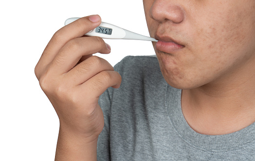 Asian student boy holding classic thermometer in mouth for measuring body temperature isolated on white background. Boy with mercury thermometer in his mouth.