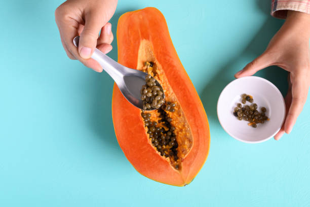 istock Hand holding spoon and remove seeds from ripe papaya fruit 1297884949