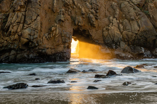 Sunset at Pfeiffer Beach in Big Sur Watching the sun set through Keyhole Arch at Pfeiffer Beach in Big Sur, California. tidal inlet stock pictures, royalty-free photos & images