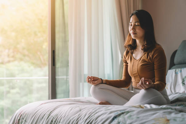 asiatica donna cinese meditando in camera da letto - meditare foto e immagini stock