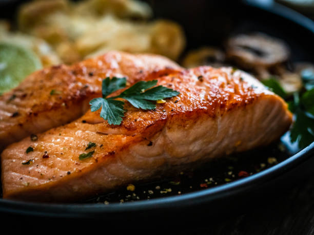 bistecche di salmone fritto, cavolfiore fritto e funghi commestibili fritti su tavolo di legno - salmon dinner foto e immagini stock