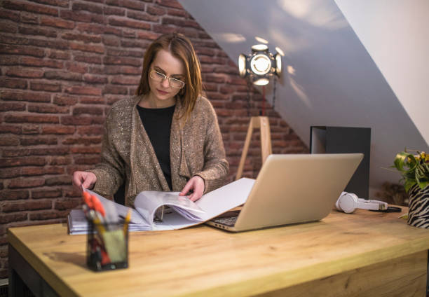 istock Businesswoman reading files from a file binder and using a laptop 1297903968