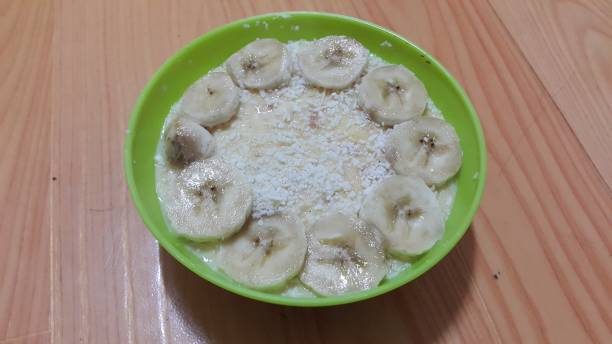 Creamy tasty sweet custard with banana pieces on surface inbowl on wooden floor Creamy tasty sweet custard with banana pieces layered on surface on wooden floor. A top view of home made custard, a dairy products for dessert after meal. hollandaise sauce stock pictures, royalty-free photos & images