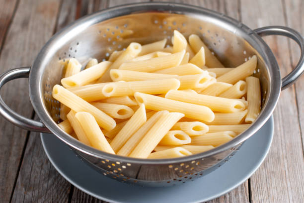 istock Fresh cooked Penne pasta in colander on table 1297908168