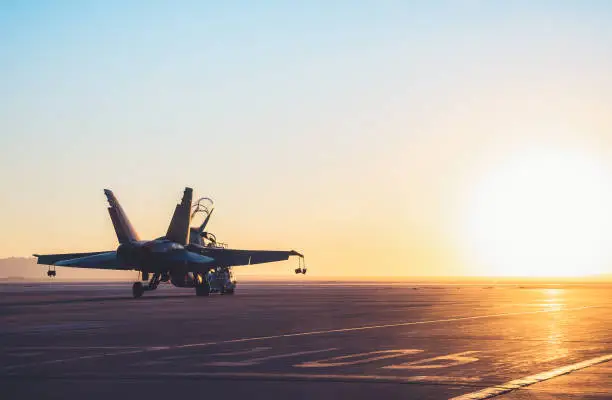 Photo of Jet fighter on an aircraft carrier deck against beautiful sunset sky .