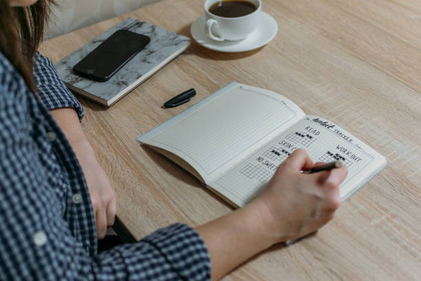 istock Bullet Journal Habit Tracker. Woman cross off day with routine in her Habit Tracker. Selective focus 1297915587