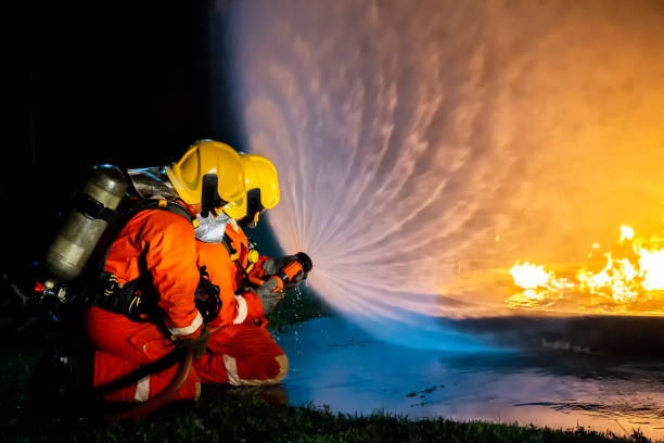 istock Firefighter training, fireman using water and extinguisher to fighting with fire flame in an emergency situation., under danger situation all firemen wearing fire fighter suit for safety. 1297915633