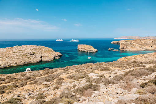 Turquoise waters of the Blue lagoon of Comino island. Rocky cliffs and blue sky is on the background.