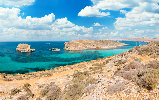 Turquoise waters of the Blue lagoon of Comino island. Rocky cliffs and blue sky is on the background.