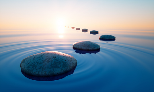 Dark stones in calm water with evening sun with horizon - tranquil scenery