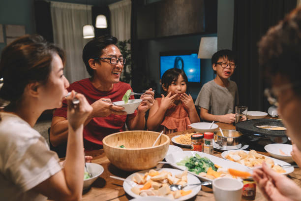 asiatische chinesische familie und cousins bei wiedersehen abendessen zu hause - chinesischer abstammung fotos stock-fotos und bilder