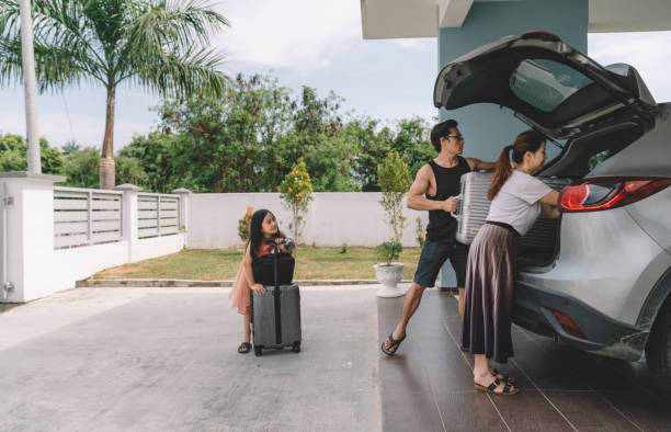 asian chinese couple unloading luggage with their daughter from their car at their house home unloading photos stock pictures, royalty-free photos & images