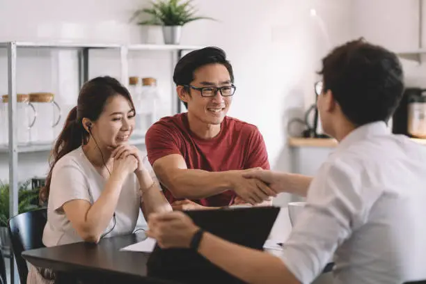 Photo of asian chinese businessman shaking hands with chinese couple in their house