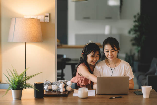 madre e hija chinas asiáticas usando computadora portátil navegando por internet en la sala de estar - mothers audio fotografías e imágenes de stock