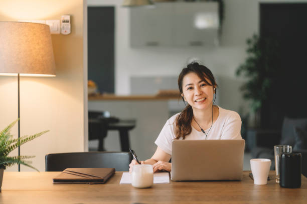 empresário mulher chinesa asiática trabalhando de casa na sala de estar olhando para a câmera sorrindo - looking at camera smiling desk isolated - fotografias e filmes do acervo