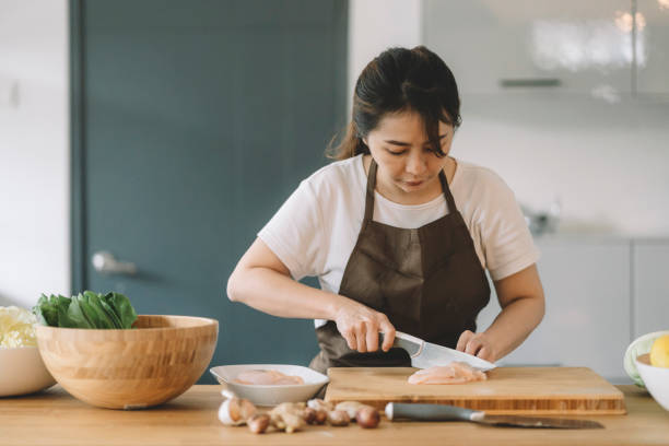 asian chinese mother cutting meat for preparing meal at kitchen