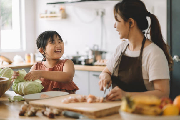 brincalhão bonito asiático filha chinesa ajudando mãe preparando comida na cozinha - chicken tender - fotografias e filmes do acervo