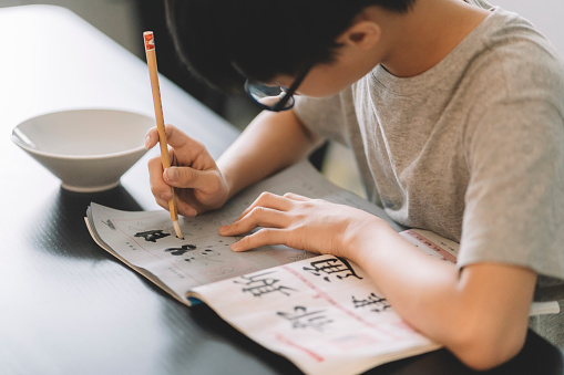 asian chinese teenager practicing chinese calligraphy at home