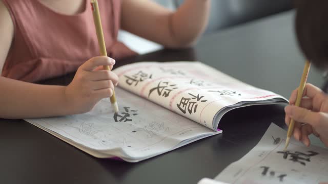 asian chinese siblings are practicing chinese calligraphy at home