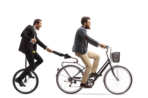 istock Man riding a unicycle and holding an umbrella behind a man with a bicycle 1297934446
