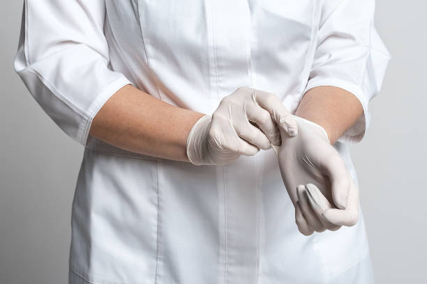 Cropped view of doctor putting a white latex gloves for protective virus. Medicine and healthcare concept Cropped view of doctor putting a white latex gloves for protective virus. Protect yourself. Medicine and healthcare concept surgical glove stock pictures, royalty-free photos & images