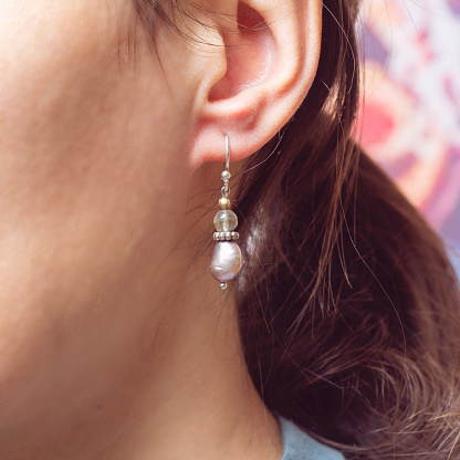 Female ear wearing beautiful elegant earring with river pearl