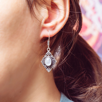 Female ear wearing beautiful elegant earring with moon stone