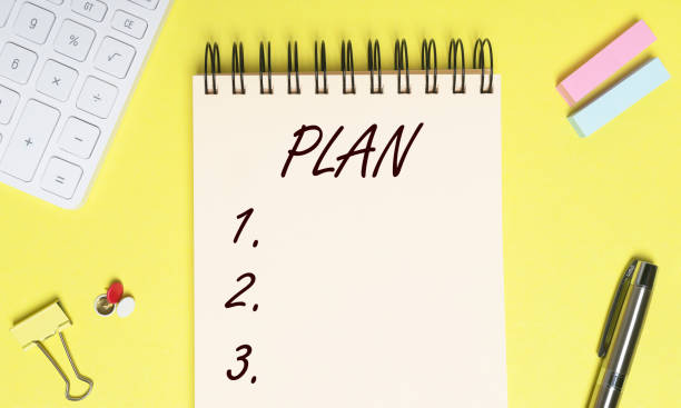 istock Plan list on yellow table. Word or inscription 1297940430