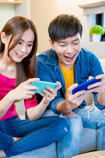 Close up of asian couple play mobile game together at home happily