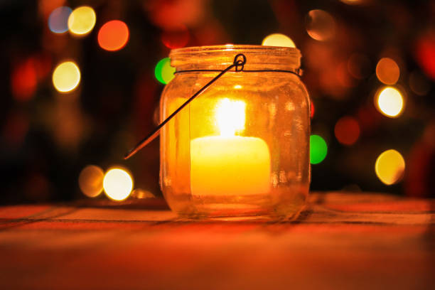 istock glass jar with lit candle inside with Bokeh lights in background. Home decoration 1297942748