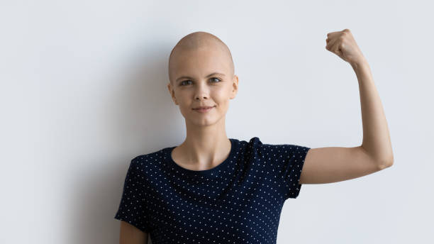 potente mujer enferma con cáncer mirando a la cámara levantando el puño - mujer luchadora fotografías e imágenes de stock