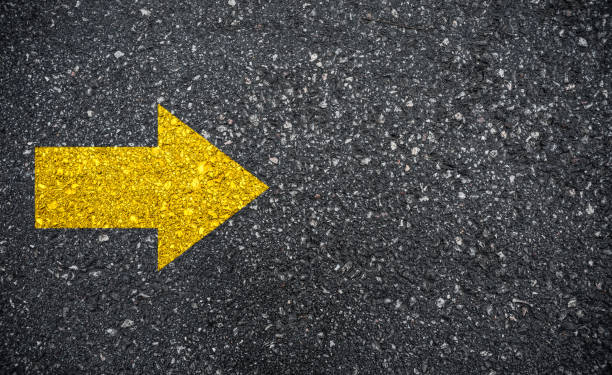 istock Yellow arrow sign on asphalt background 1297948489