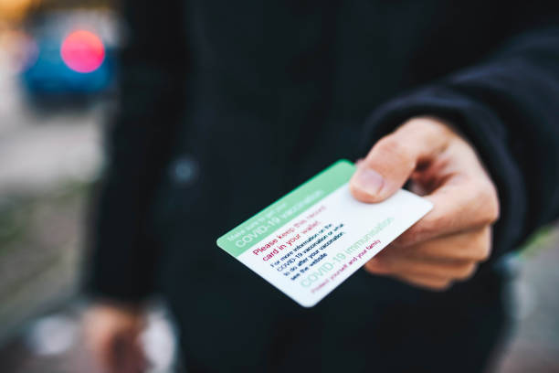 istock Unrecognizable man holding a vaccination card for Covid 19 immunization. Coronavirus pandemic concept. Vaccination ID card close up. 1297949326