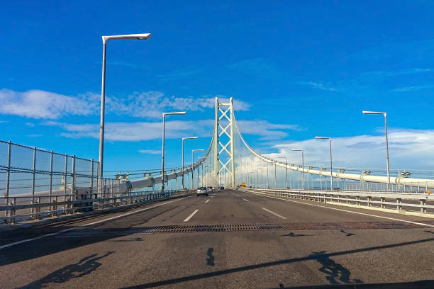 проезжая по мосту акаси кайкио в солнечный день - kobe bridge japan suspension bridge стоковые фото и изображения