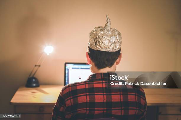 Conspiracy Theory Concept Young Man With Aluminum Cap Searching The Internet Sitting Lonely In The Dark Basement Stock Photo - Download Image Now