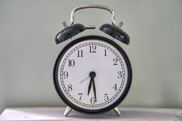 istock The time is 5:30 am or pm. Retro clock isolated wooden table. Half past five. 1297953154