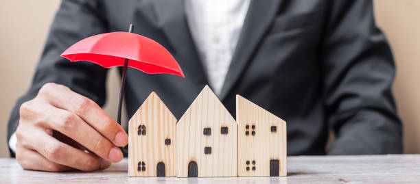 Businessman hand holding red Umbrella cover wooden Home model on table office. Property insurance and real estate concepts Businessman hand holding red Umbrella cover wooden Home model on table office. Property insurance and real estate concepts home insurance stock pictures, royalty-free photos & images