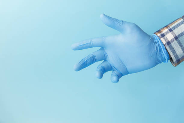 istock Doctor hand with glove on blue background. 1297959236
