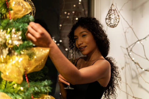 istock Woman drinking champagne while looking at the christmas tree 1297960397