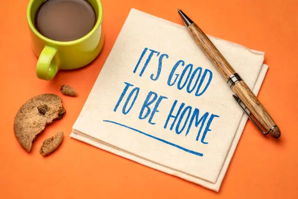 It is good to be home - positive note. Handwriting on a napkin with a cup of coffee and cookie. Stay at home concept.