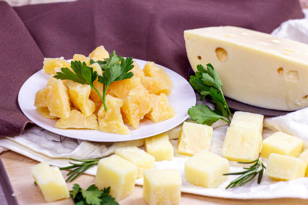 다양한 파마산과 마스담이 가벼운 배경에 부엌에서 치즈를 조각합니다. - cheese block gouda dutch culture 뉴스 사진 이미지
