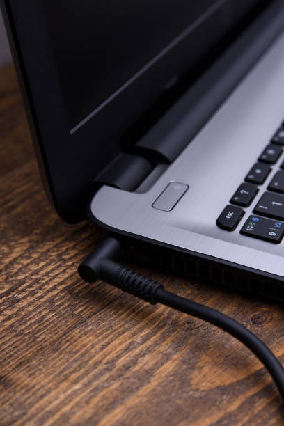 istock Laptop, computer is charging from a 220-volt outlet on a desk near the wall. Energy, accumulation. Mockup 1297967320