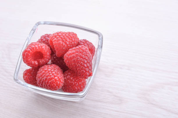 istock Raspberries in a bowl on a wooden textured background 1297975427