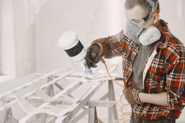 istock Carpenter in his paint room spraying a piece of wood 1297980708