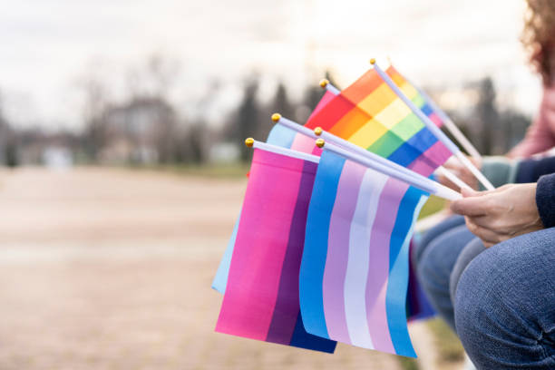 multiple pride flags hold by people - gay pride flag fotos imagens e fotografias de stock