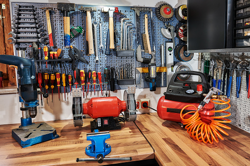 A collection of assorted tools hanging on the wall with a work bench